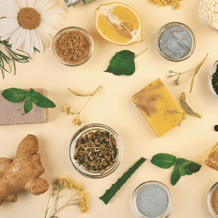 Various natural ingredients including herbs, a lemon, and a bar of soap on a light background
